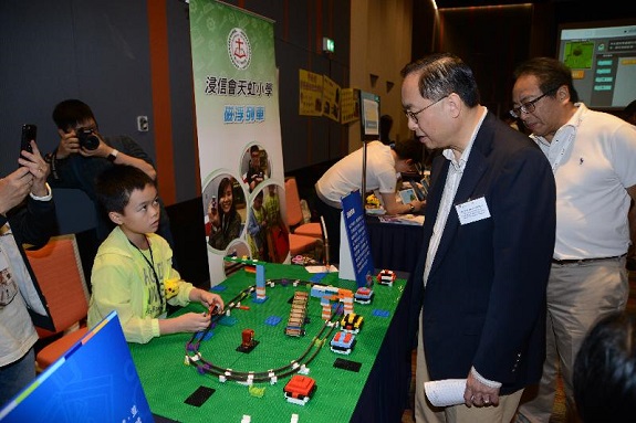 创新及科技局局长杨伟雄（右二）今日（十二月四日）出席香港城市大学应用程式实验室举办的「编程一小时」香港区两周年典礼，参观摊位，听取浸信会天虹小学的同学介绍作品。 