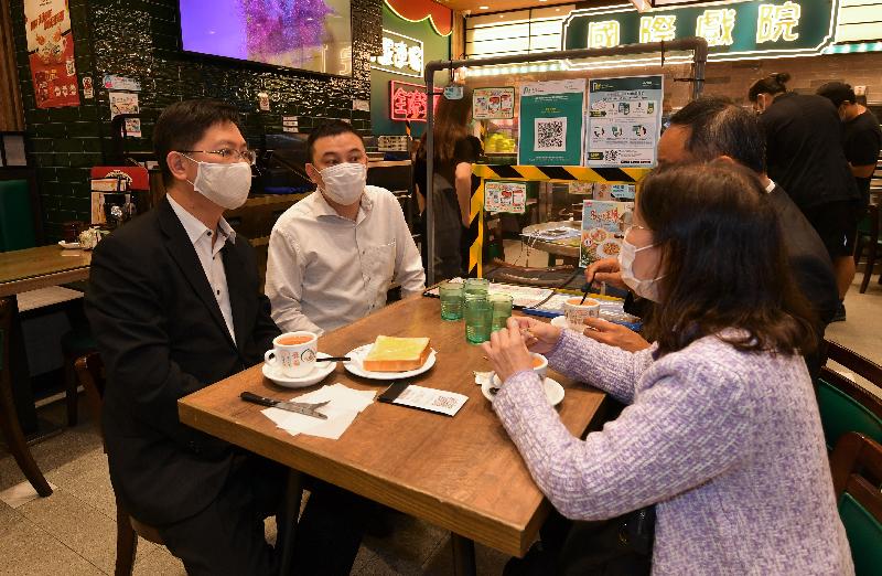 創新及科技局局長薛永恒（左一）今日（十一月十八日）在九龍城區一間茶餐廳視察「安心出行」流動應用程式的使用情況，並與茶餐廳店主傾談。旁為食物環境衞生署副署長黃淑嫻（右一）。