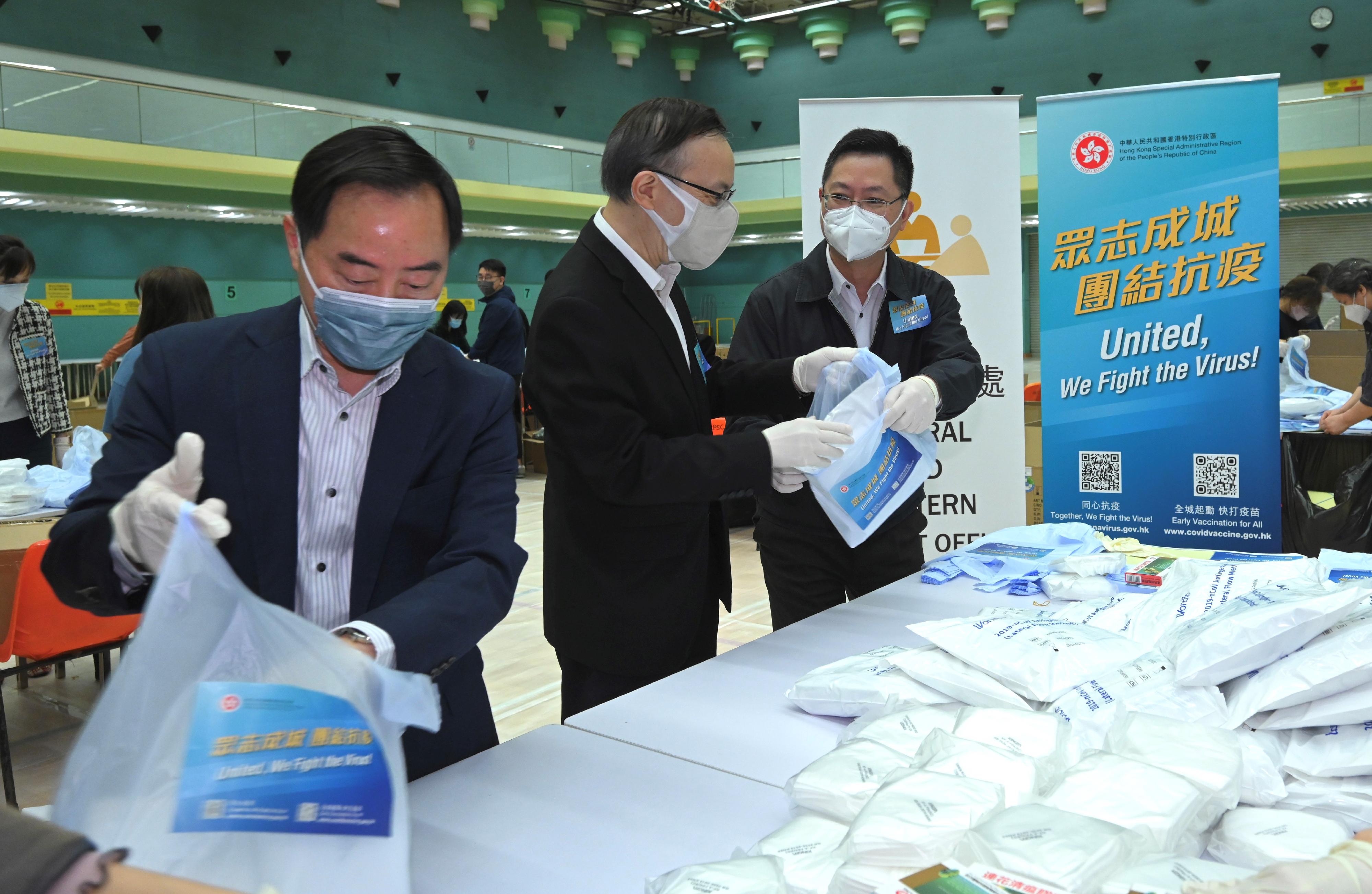 The Secretary for Innovation and Technology, Mr Alfred Sit (right); the Government Chief Information Officer, Mr Victor Lam (centre); and the Deputy Government Chief Information Officer, Mr Tony Wong (left), engage in the packaging work of anti-epidemic service bags at the Hong Kong Park Sports Centre today (March 31).