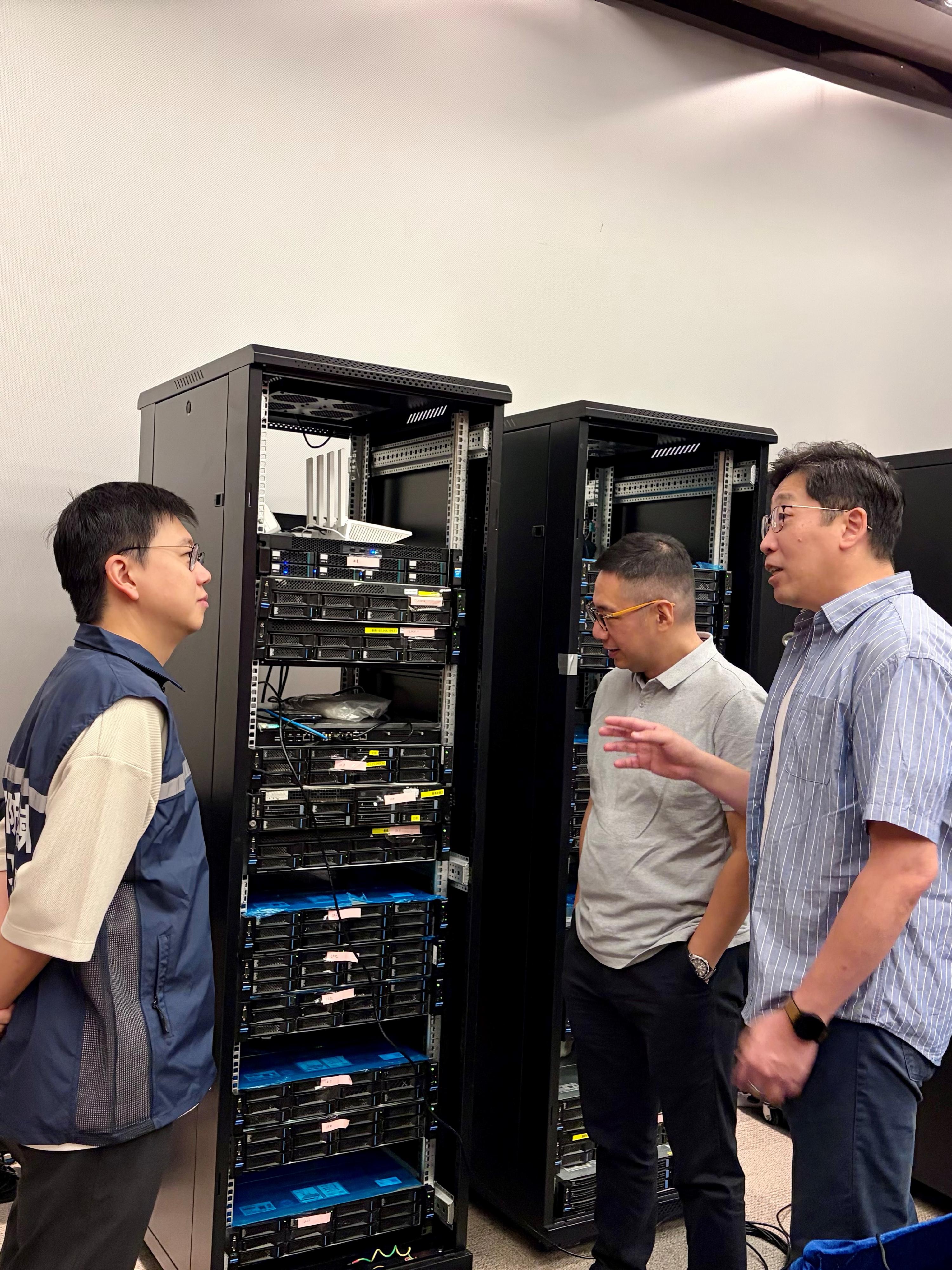 「香港網絡安全攻防演練—以攻築防2025」進行期間，副數字政策專員（數字基建）張宜偉（右）到場並聽取工作人員介紹活動進度。